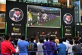 都内で行われた家庭用ゲーム機「プレイステーション4（PlayStation 4、PS4）」用サッカーゲーム「FIFA 14  2014 FIFA World Cup Brazil  Limited Pack」の発売イベントで、大型スクリーンに映ったゲーム画面を眺めるサッカーファンら（2014年6月4日撮影）。(c)AFP/Yoshikazu TSUNO