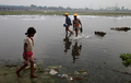 インド・ニューデリー（New Delhi）市内を流れるガンジス川の最大支流、ヤムナー川（Yamuna River）を歩いて渡る建設作業員2人（中央、2012年7月14日撮影）。(c)AFP/Andrew Caballero-Reynolds