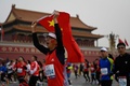 国旗を掲げながら天安門広場を駆ける北京マラソンの出場ランナー（2022年11月6日撮影）。(c)Jade Gao/ AFP