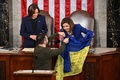 米連邦議会で、ナンシー・ペロシ下院議長（右）にウクライナ国旗を贈るウォロディミル・ゼレンスキー大統領（手前）と、それを見つめるカマラ・ハリス米副大統領（後列左、2022年12月21日撮影）。(c)Mandel NGAN / AFP