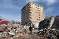 地震の被害を受けたトルコ・カフラマンマラシュで、倒壊した建物の間を歩く男性（2023年2月7日撮影）。(c)Adem ALTAN / AFP