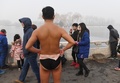 スモッグに覆われた中国・北京の湖で泳いだ後に体を乾かす男性（2017年1月1日撮影）。(c)AFP/GREG BAKER
