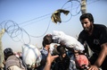シリア内戦を逃れ、国境のフェンス越しに子どもをトルコに不法入国させる避難民の男性。トルコ南東部シャンルウルファ県アクチャカレにある国境検問所付近にて（2015年6月14日撮影）。(c)AFP / Bulent Kilic