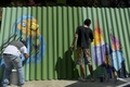 南米コロンビア・メデジン（Medellin）の最貧国地区のひとつ「コムーナ13（Comuna 13）」の建物に絵を描くアーティストら（2014年4月1日撮影）。(c)AFP/Raul ARBOLEDA