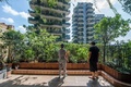 中国四川省成都で、植物に覆われた集合住宅のベランダを別のベランダから眺める住民ら（2020年8月3日撮影）。(c)STR / AFP