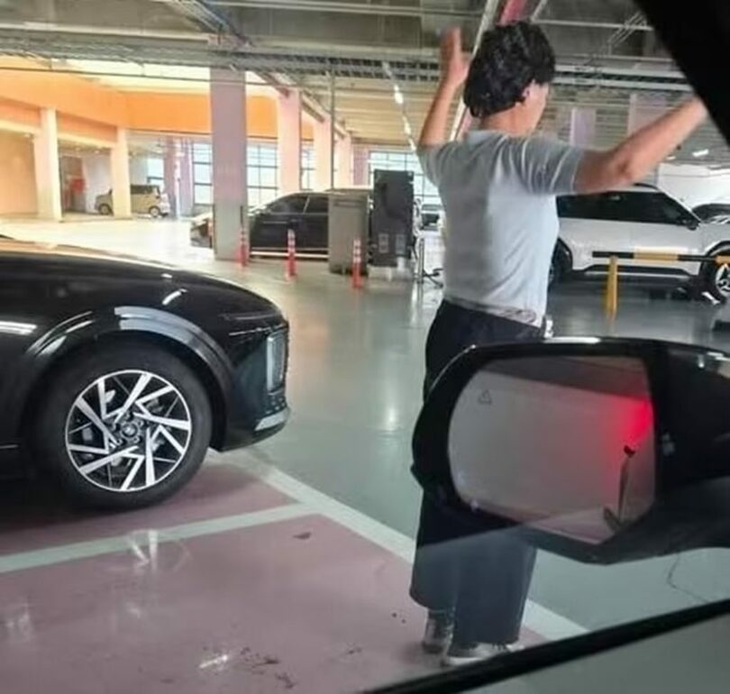 空いている駐車スペースに立ち、両腕を広げて場所を確保する女性＝オンラインコミュニティ(c)news1