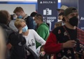 米カリフォルニア州ロサンゼルスの空港でチェックインのため並ぶ旅行客（2021年12月23日撮影）。(c)DAVID MCNEW / AFP