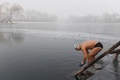 スモッグに覆われた中国・北京の湖で泳ごうとする男性（2017年1月1日撮影）。(c)AFP/GREG BAKER