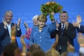 独ベルリン（Berlin）のキリスト教民主同盟（Christian Democrats、CDU）本部で、総選挙の出口調査結果第1報をうけ花束を掲げるアンゲラ・メルケル（Angela Merkel）首相（2013年9月22日撮影）。(c)AFP/JOHANNES EISELE