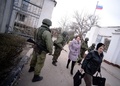 ウクライナ南部クリミア（Crimea）半島のNovoozerneで、ロシア兵とみられる部隊に制圧されたウクライナ海軍基地を去る女性ら（2014年3月19日撮影）。(c)AFP/Filippo MONTEFORTE