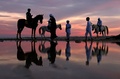 アラブ首長国連邦（UAE）の首都アブダビで、夕焼け空の下、馬に乗る人々（2022年2月8日撮影）。(c)Karim SAHIB / AFP
