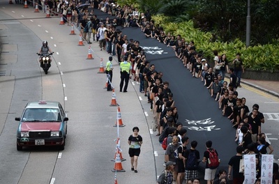 中国政府に「不服従」、黒い布掲げデモ行進 香港