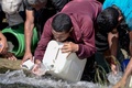 ベネズエラの首都カラカスで、破裂した水道管から下水用水路へと流れ込む水をくむ人たち（2019年3月11日撮影）。(c)JUAN BARRETO / AFP