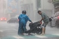大雨の中、転倒したバイクの運転手を助ける人。台湾・基隆で（2024年10月31日撮影）。(c)I-Hwa CHENG / AFP