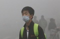 スモッグに覆われた中国東北部・黒竜江（Heilongjiang）省ハルビン（Harbin）で、マスクを着用して歩く男性（2013年10月21日撮影）。(c)AFP