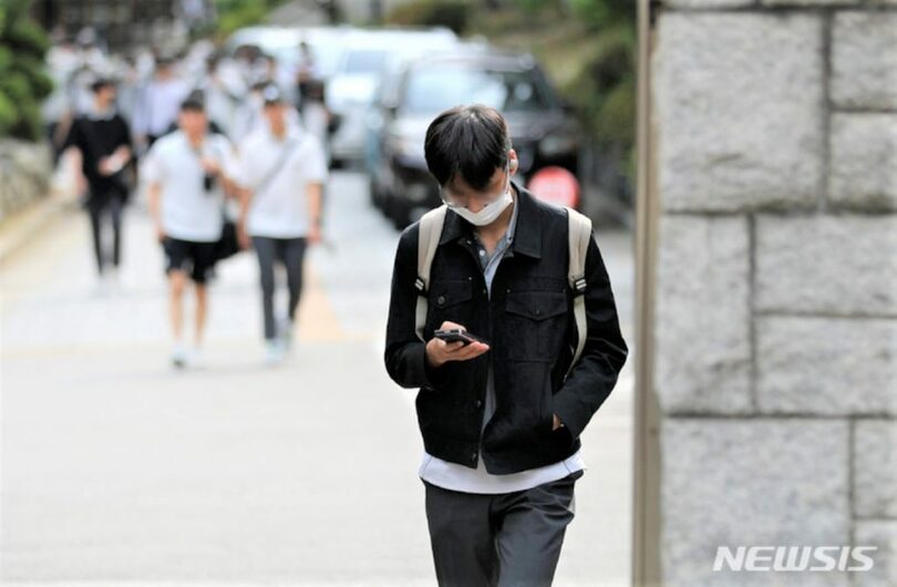 ソウルのある中学校前でスマートフォンを見ながら下校する生徒ら(c)NEWSIS