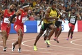 第15回世界陸上北京大会、男子4×100メートルリレー決勝。米国のタイソン・ゲイ（左奥）とマイク・ロジャーズ（左手前）がバトンパスをする中、走り抜けるジャマイカのウサイン・ボルト（中央、2015年8月29日撮影）。(c)AFP/WANG ZHAO