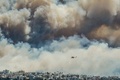 山火事の煙が漂うアテネ上空を飛行する消防ヘリコプター（2015年7月17日撮影）。(c)AFP/ANDREAS SOLARO
