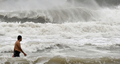 香港の浜辺で、台風の接近するなか、泳ぐ男性（2008年8月22日撮影）。(c)AFP/CONNOR CLARKE
