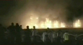 パキスタンの首都イスラマバード（Islamabad）で、爆弾の爆発で火の手が上がるマリオットホテル（Marriott Hotel）を見る救急隊員と野次馬（2008年9月20日、パキスタンのGEO TVが放送した映像を撮影したもの）。(c)AFP/GEO TV