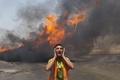 パレスチナ自治区ガザ地区（Gaza Strip）で、イスラエル軍の攻撃で炎上した国連（UN）倉庫の消火活動にあたるパレスチナ人の消防隊員（2014年7月12日撮影）。(c)AFP/MAHMUD HAMS
