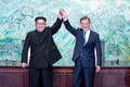 韓国と北朝鮮の軍事境界線上の板門店で、一緒に手を挙げる韓国の文在寅（ムン・ジェイン）大統領（右）と北朝鮮の金正恩（キム・ジョンウン）朝鮮労働党委員長（2018年4月27日撮影）。(cAFP PHOTO / KOREAN BROADCASTING SYSTEM