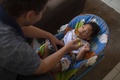 ブラジル・リオデジャネイロの自宅で、小頭症と診断された息子に離乳食を与える父親のワラシさん（2018年11月30日撮影）。(c)Mauro PIMENTEL / AFP