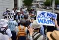 横浜市で開かれた安全保障関連法案に関する地方公聴会の会場前でプラカードを掲げて同法案に抗議する人々（手前）の通行を止める警官ら（2015年9月16日撮影）。(c)AFP/Yoshikazu TSUNO