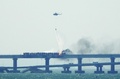 クリミア半島とロシアを結ぶ橋でトラック爆発後に火災が発生し、消火活動に当たるヘリコプター（2022年10月8日撮影）。(c)AFP
