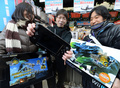 任天堂（Nintendo）は8日、家庭用ゲーム機「Wii」の第2世代となる「Wii U」を発売した。全国の家電販売店には同ゲーム機をいち早く手にしようと数百人が列を成した。

写真は、都内の販売店でWii Uを手にポーズする人々（2012年12月8日撮影）。(c)AFP/Toru YAMANAKA