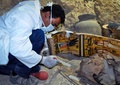 エジプト南部ルクソール近くの3500年前の墓で見つかった木棺を前に作業する考古学者（2017年4月18日撮影）。(c)AFP