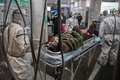 中国・武漢の紅十字会医院で、患者を運び込む防護服姿の医療関係者（2020年1月25日撮影）。(c)Hector RETAMAL / AFP