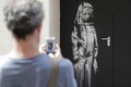 パリ市内の劇場バタクランの非常口に描かれたバンクシー作品を写真撮影する男性（2018年6月25日撮影、資料写真）。(c)Thomas SAMSON / AFP