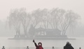 スモッグに覆われた中国・北京の湖の畔で自撮りする男性（2017年1月1日撮影）。(c)AFP/GREG BAKER