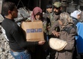 シリア首都ダマスカス（Damascus）のヤルムーク（Yarmuk）・パレスチナ人難民キャンプで、国連パレスチナ難民救済事業機関（UNRWA）から食糧物資の配給を受ける人々（2014年1月30日撮影）。(c)AFP/HO/SANA