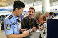 北京首都国際空港で、入国カードを記入する米国の観光客を手助けする辺防検査站（出入境検査所）の警察官（2024年7月10日撮影）。(c)Xinhua News