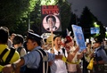 東京の国会議事堂前で、衆議院平和安全法制特別委員会が可決した安全保障関連法案に抗議するデモに参加した市民団体のメンバーを押し戻す警官（2015年7月15日撮影）。(c)AFP/Yoshikazu TSUNO