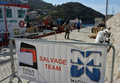 イタリア中部ジリオ（Giglio）島付近の浅瀬で1月に座礁、32人が死亡・行方不明になり、船体の半分が沈没したまま放置されていたクルーズ船「コスタ・コンコルディア（Costa Concordia）号」の引き揚げ作業が今週開始された。

写真はジリオ島の岸から見える「コスタ・コンコルディア（Costa Concordia）号」の引き揚げ作業の準備を始めた米サルベージ会社タイタン・サルベージ（Titan Salvage）と伊ミコペリ（Micoperi）の作業員ら（2012年6月25日撮影）。(c)AFP/VINCENZO PINTO