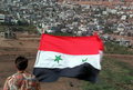 シリアの国旗を掲げイスラエルの占領下にあるMajdalの町並みを見下ろす男性（1997年10月12日撮影）。(c)AFP/LOUAI BESHARA