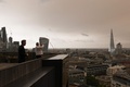 英ロンドンで、会社のバルコニーから暗くなった空の写真を撮る男性（2017年10月16日撮影）。(c)AFP/Daniel SORABJI