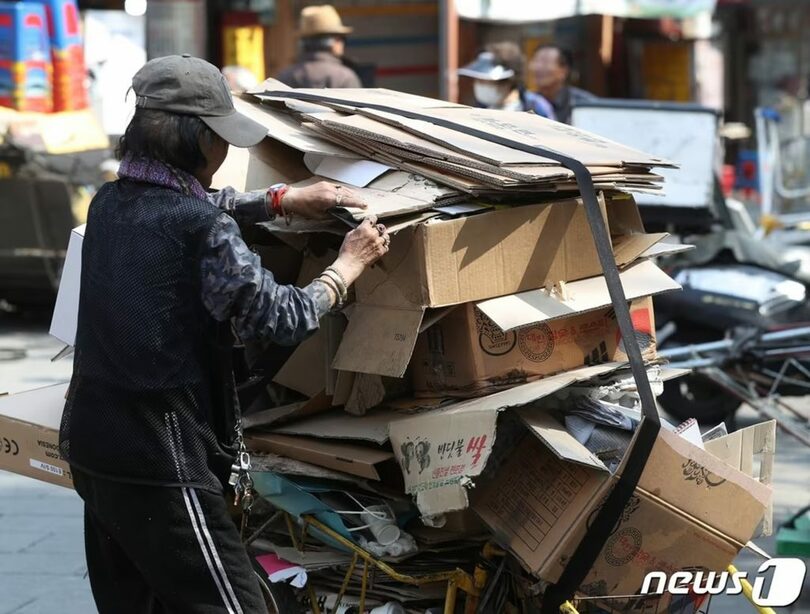 ソウル市内の古紙回収業者の前で、荷車に積まれた古紙を整理する高齢者 (c)news1