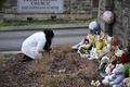 米テネシー州ナッシュビルの小学校コブナント・スクール前で、銃乱射事件の犠牲者のために手向けられた花束などの前にしゃがみ込む女性（2023年3月28日撮影）。(c)Brendan SMIALOWSKI / AFP