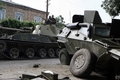 グルジア・南オセチア（South Ossetia）自治州のツヒンバリ（Tskhinvali）で、戦闘で破壊されたグルジア軍装甲車両のそばを通過するロシア軍戦車（2008年8月11日撮影）。(c)AFP/ANDREI SMIRNOV