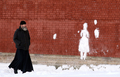 ロシア・サンクトペテルブルク（Saint Petersburg）、ペトロパヴロフスク要塞（Saint-Peter and Paul fortress）の壁に雪で作られた人型を眺める、ロシア正教会の司祭（2011年1月20日撮影）。(c)AFP/KIRILL KUDRYAVTSEV