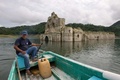 メキシコ南東部のチアパス州で、ダム貯水池の水位が下がり、再び姿を現したサンティアゴ教会の近くを航行するボート（2015年10月21日撮影）。(c)AFP/Mario Vazquez de la Torre
