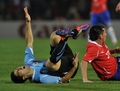 コパ・アメリカ2011（2011 Copa America）1次リーグC組、ウルグアイ対チリ。厳しいチェックを受けピッチに倒れるウルグアイのルイス・スアレス（Luis Suarez、左、2011年7月8日撮影）。(c)AFP/RODRIGO ARANGUA
