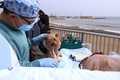 スペイン・バルセロナのバルセロネータ海岸の遊歩道で、飼い犬の「ルナ」をなでるマルタ・パスクアルさん。新型コロナウイルス感染症（COVID-19）にかかったパスクアルさんが、新鮮な空気を吸えるようにと、病院スタッフが外に連れ出した（2021年3月4日撮影）。(c) LLUIS GENE / AFP