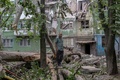 早朝、ロシア軍の攻撃で破壊された建物の外に立つ住民。ウクライナ東部ドネツク州コンスタンチノフカで（2022年8月6日撮影）。(c)Bulent KILIC / AFP
