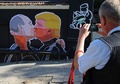 リトアニアの首都ビリニュスで、キスをするドナルド・トランプ氏とウラジーミル・プーチン大統領が描かれた壁画の写真を撮る男性（2016年5月13日撮影）。(c)AFP/Petras Malukas