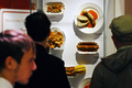 ドイツ・ベルリン（Berlin）で、ソーセージにケチャップとカレー味のソースをかけた名物料理「カリーブルスト（Currywurst）」の調理法と歴史を紹介する博物館「ドイツ・カリーブルスト博物館（German Currywurst Museum）」が、15日にオープンする。写真は、オープンに先駆けてカリーブルストの展示を見学する来場者（2009年8月13日撮影）。(c)AFP/DDP/MICHAEL GOTTSCHALK